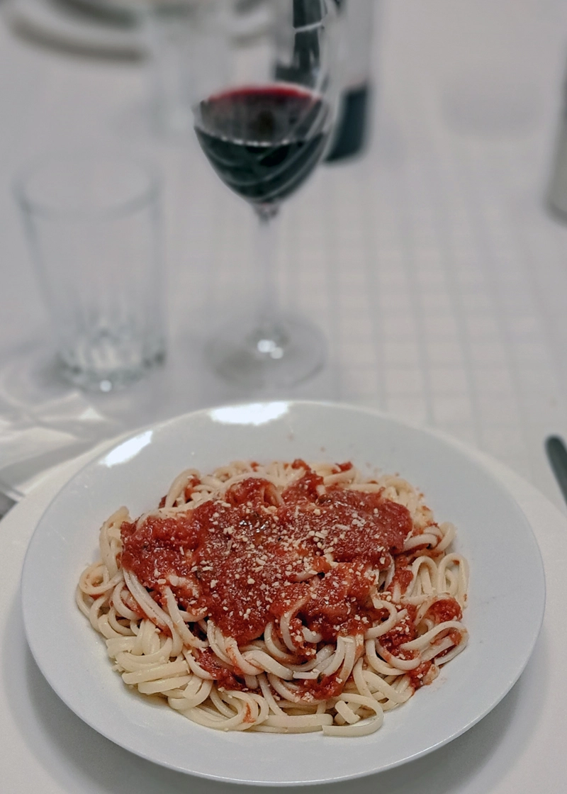 Image of a homemade pasta and glass of red wine.