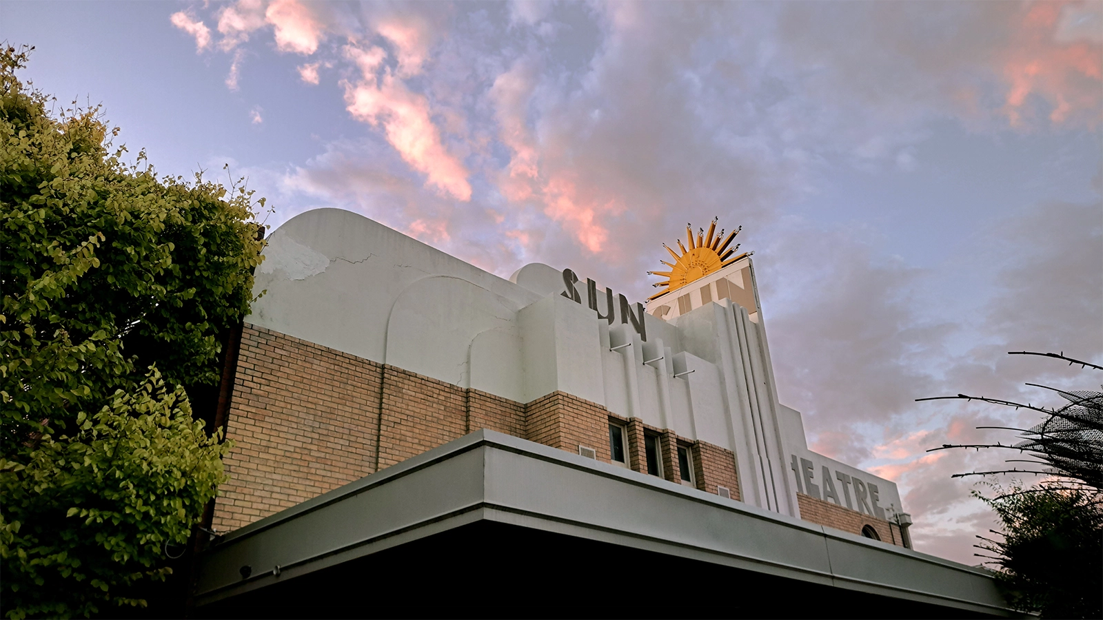 Photo of the Sun Theatre in Yarraville. Late in the evening with pick clouds in the sky. Photo by local architect Matthew Oczkowski.
